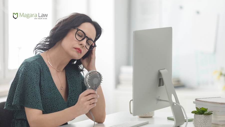 A woman cooling down using a fan amid a heatwave at work.